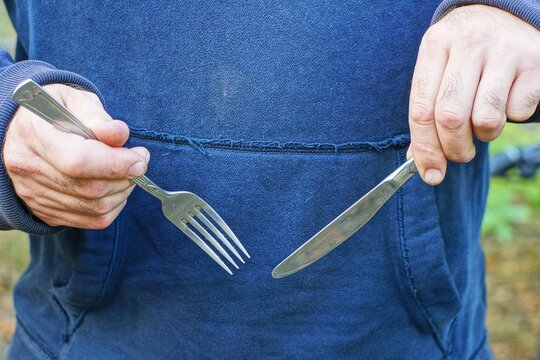 silver patterned iron tableware shiny  with handle kitchen industrial knife  with sharp fork in hands of  hungry man in blue raglan daytime outdoors