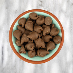 Fototapeta premium Bowl filled with milk chocolate chips on a gray marble background.