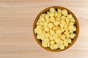 Overhead view of white baking chips in a bowl on a wood tabletop.