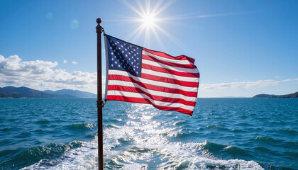 American flag flying on boat with sun shining over ocean waves and mountains in background