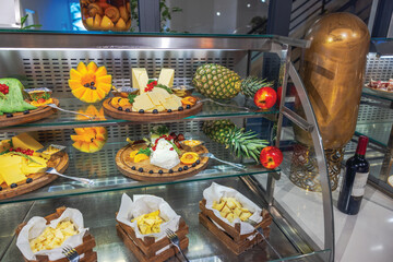 Cheese and fruit display with pineapples, apples and mango slices arranged on buffet counter hotel. Curacao.