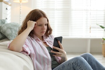 Beautiful teenage girl using smartphone on floor at home