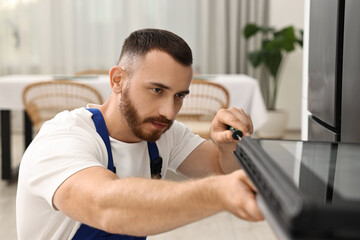 Fototapeta premium Repairman with screwdriver fixing oven at home