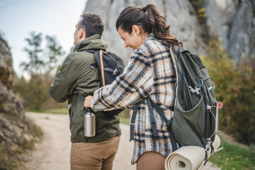 Girlfriend help boyfriend to pack and fasten his backpack