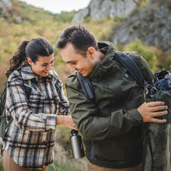 Girlfriend help boyfriend to pack and fasten his backpack