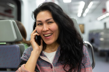 Asian woman traveler talking on mobile phone in subway train car