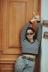 Confident Woman in Sunglasses Posing by Wooden Door