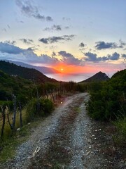 Gravel road overlooking sunset over ocean 
