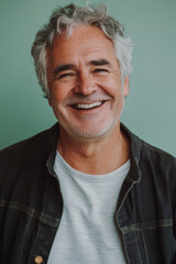 Obraz premium Candid smiling senior Caucasian man, grey hair and joyful smile, a soft pastel green background, creating a warm and inviting social media avatar.