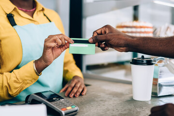 Cheerful barista taking credit card from customer