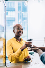Cheerful black woman taking beverage from barista