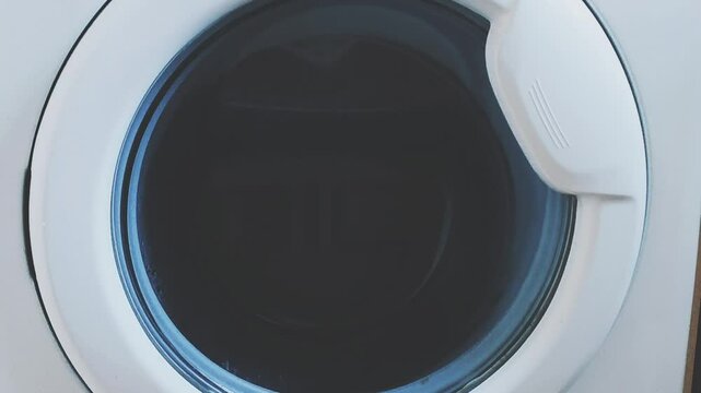 The laundry is spinning in the drum of the washing machine.