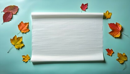 Fototapeta premium crisp white paper adorned with fall leaves on a turquoise backdrop