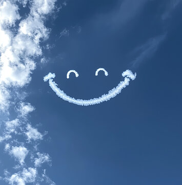 smiley face shaped clouds skywriting in the blue sky 