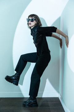 Stylish woman in black outfit and sunglasses posing dynamically