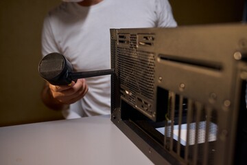 A man cleans a computer case with a vacuum in a bright room, stressing workspace tidiness