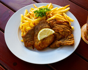 Breaded pork schnitzel with fried potatoes and greens - Czech cuisine