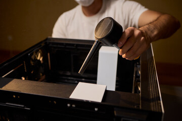 A man cleans a computer case with a vacuum in a bright room, stressing workspace tidiness