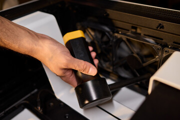 A man cleans a computer case with a vacuum in a bright room, stressing workspace tidiness