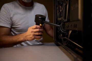 A man cleans a computer case with a vacuum in a bright room, stressing workspace tidiness