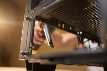 A man cleans a computer case with a vacuum in a bright room, stressing workspace tidiness