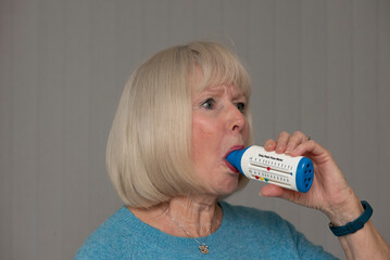 England UK. 10.11.2023.  Woman using a peak flow meter to check for Asthma symptoms.
