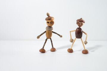 Two acorn figurines side by side, representing folk art style. Unique, handcrafted sculptures made from natural materials. Ideal for seasonal decor, DIY inspiration, and rustic art collections