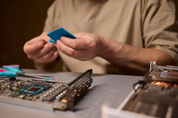Fototapeta premium Hand Repairing a Graphics Card through the Application of Thermal Paste for Better Performance