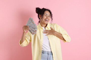 Happy woman with dollar banknotes on pink background