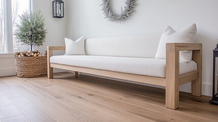 A light wooden console table showcases a lantern and potted tree, while a silver star wreath hangs above it. Wicker baskets of firewood add warmth to the airy space