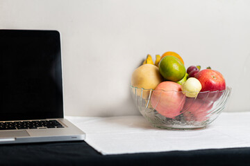 Bowl of Fresh Fruits Next to a Laptop
