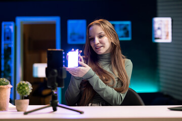 Smiling internet show host using smartphone camera on phone holder to film content about best video production tools on the market. Media star recording mini led lights review