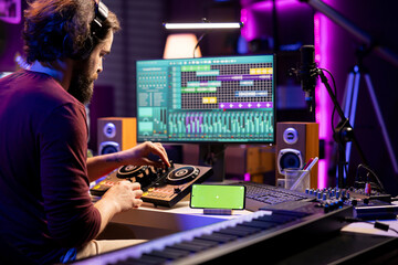 Music producer watching tutorial online and learning to mix sounds on mixing console, practicing on...