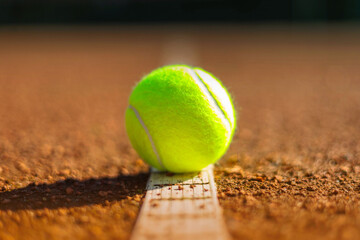 Yellow tennis ball on white strip marked court outdoor summer ground closeup