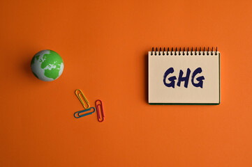 There is notebook with the word GHG. It is an abbreviation for Greenhouse Gas as eye-catching image.