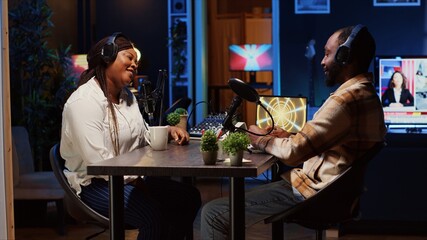 Woman hosting podcast, using professional audio equipment to ensure high sound quality during live discussion with guest. Internet show presenter talking with man, broadcasting from home studio