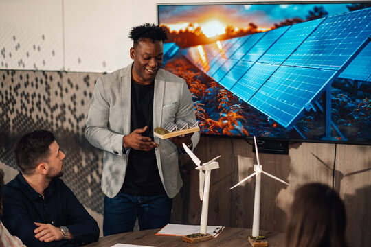 Diverse businessman with solar panel model having seminar at boardroom