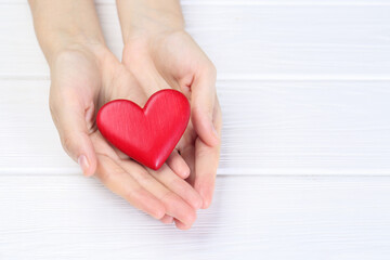 Obraz premium Woman holding red heart at white wooden table, closeup. Space for text
