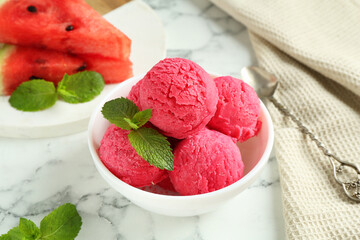Scoops of tasty watermelon sorbet with mint in bowl on white marble table, closeup