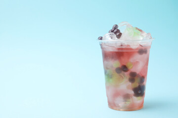 Tasty bubble tea in plastic cup on light blue background, space for text