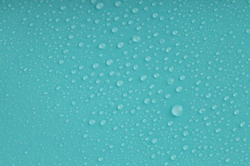 Water drops on turquoise background, top view