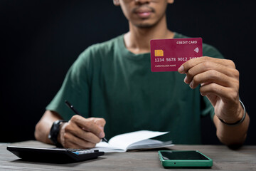 Showing a Man holding a credit card and using a calculator, the concept of accounts and savings.