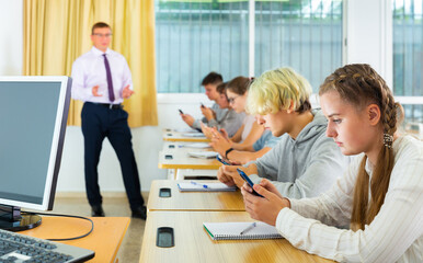 Obraz premium Side view of student group working with mobile phones in school class