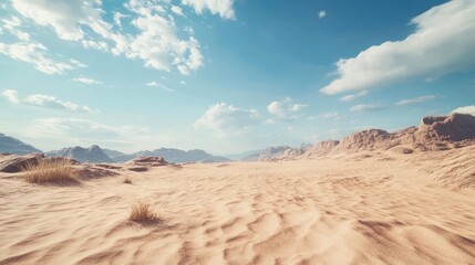 Fototapeta premium A vast, sandy desert landscape stretches out under a clear blue sky with fluffy white clouds.