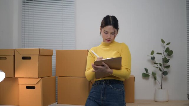 Young woman organizing home office with cardboard boxes