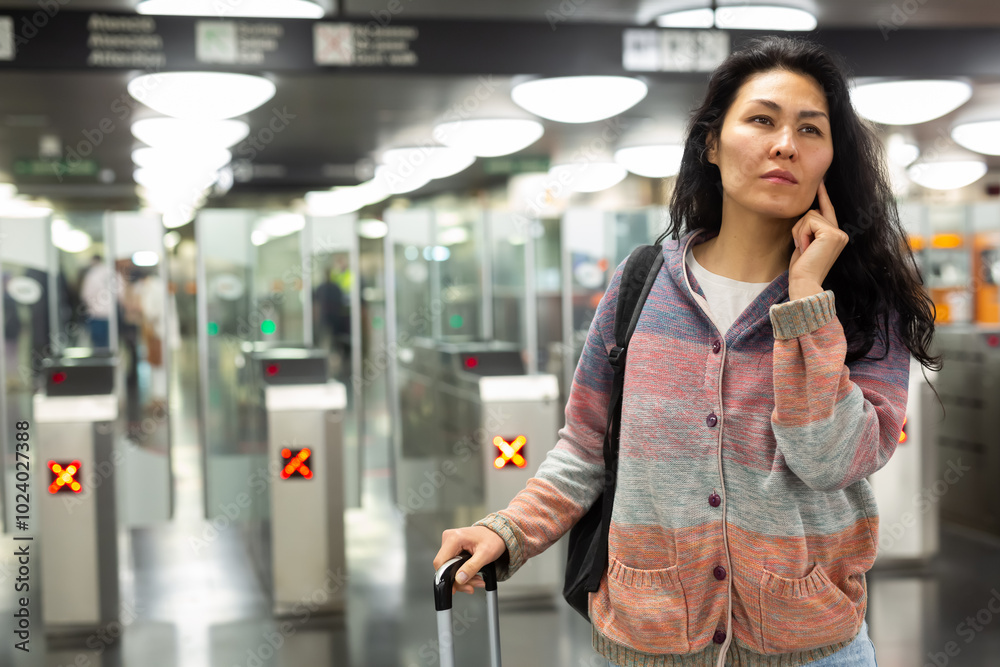 Wall mural Asian woman passing through ticket gates in a public transportation station