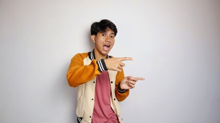 casual shocked young handsome Asian man wearing a jacket giving a gesture pointing to the side