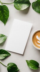Blank card and latte with green leaves on white textured background