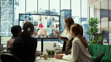 Business team in a boardroom attend videocall meeting with investors group, discussing about increasing funds for a global development plan. Staff and shareholders on teleconference. Camera B.
