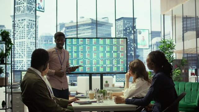 Businessman announces company bankruptcy during a meeting, explains collapse and job losses to worried employees as financial data on the screen reflects economic failure and insolvency. Camera B.
